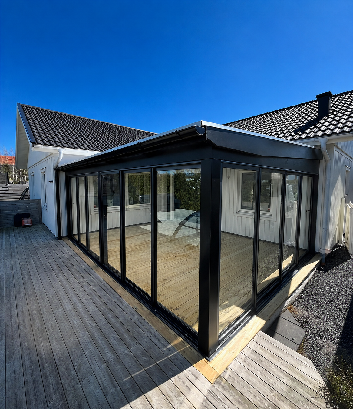 Färdigt inglasat uterum med svart plåttak på villa